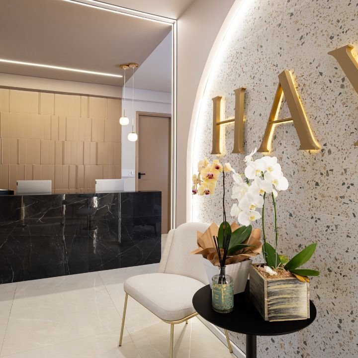 Recepção da clínica, com bancada em mármore preto e orquídeas